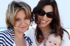 two beautiful girls with a baby on the beach